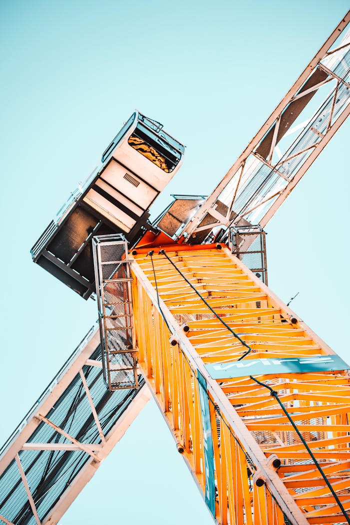 about-03 A striking low angle shot of a vibrant yellow tower crane against a clear sky, showcasing industrial power.